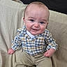 baby, child, infant, smiling, portrait, sitting, chair, couch, cushion, clothing, plaid_shirt, beige_pants, fashion, indoors, face, eyes, happy, photograph, furniture, family