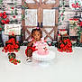 toddler, birthday_cake, pink_cake, red_outfit, strawberries, red_roses, wooden_door, birthday, celebration, flower_decor, cake_stand, white_floor, child, portrait, indoors, decorative, cute, festive, girl, party
