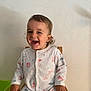 toddler, child, smiling, onesie, animal_print, chair, indoor, happy, cute, person, sitting, clothing, baby, eating, skin, head, hair, earrings, face, expression