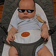 Asher joined the competition — help win amazing prizes! baby, infant, sunglasses, pixelated, baby_seat, gray, clothing, legs, hands, wooden_floor, indoor, casual, cute, face, child, baby_boy, onesie, comfort, relaxed, serious