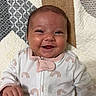 Adeline joined the competition — help win amazing prizes! baby, smile, infant, onesie, rainbow_pattern, quilt, geometric_pattern, happy, face, skin, hand, clothing, lying_down, cute, child, portrait, indoor, closeup, young, person