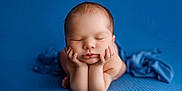 Raylan joined the competition — help win amazing prizes! baby, newborn, sleeping, hands, chin, blue_background, soft_texture, portrait, cute, peaceful, infant, skin, resting, closeup, child, tiny_fingers, studio_photo, calm, adorable, pose