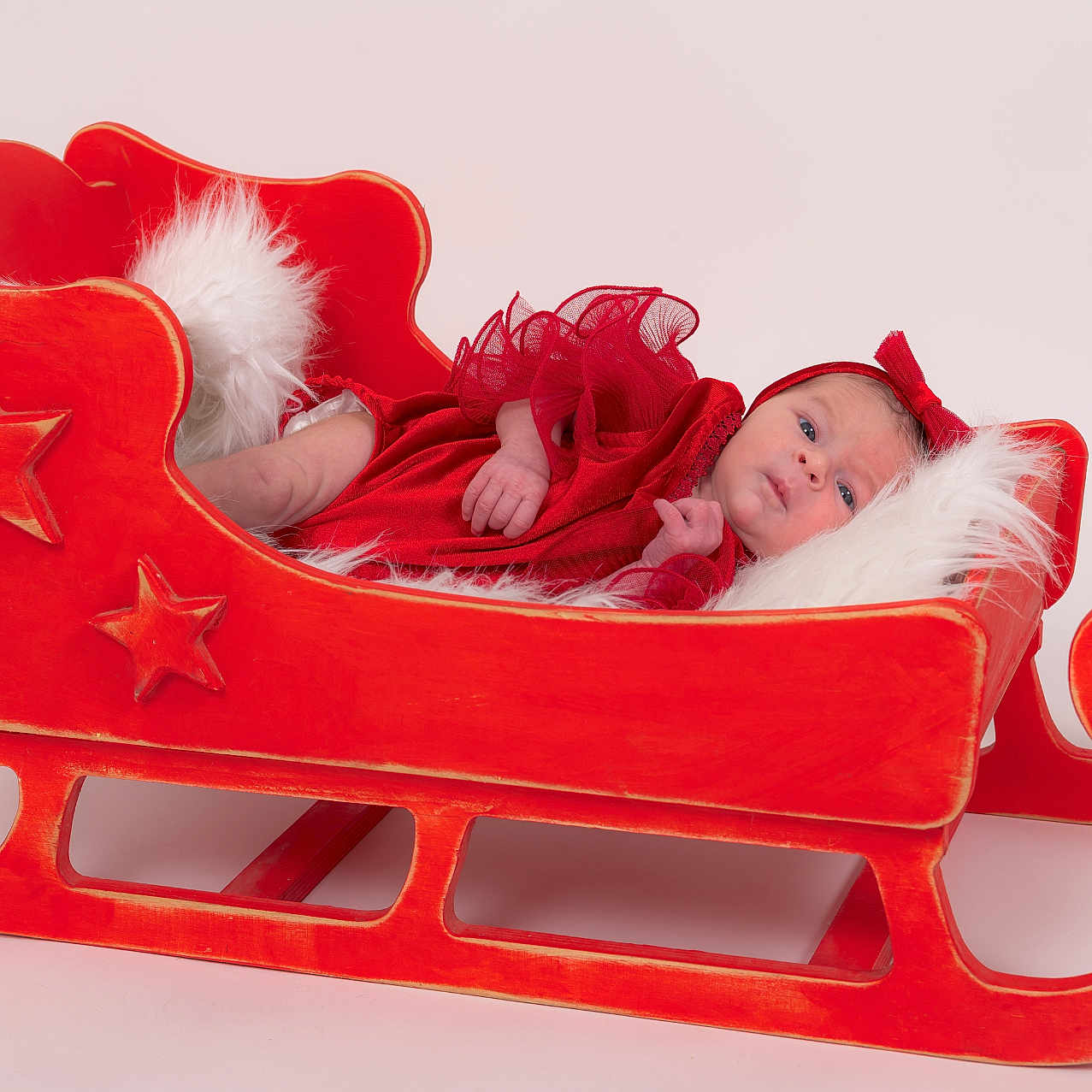 Nina participe au concours pour gagner de l'argent avec cette photo : baby, child, cute, decor, festive, headband, holiday_theme, indoor, infant, newborn, portrait, pose, red_clothing, resting, smiling, soft_texture, stars, studio, white_cushion, wooden_sleigh