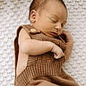 newborn, baby, sleeping, knitted_outfit, brown_clothing, blanket, soft_texture, peaceful, infant, portrait, closeup, cute, resting, cozy, child, sleep, relaxation, indoors, person, newborn_baby