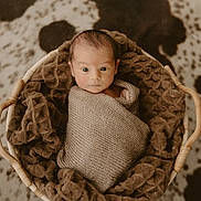 Colter is registered to the contest to win money with this photo: newborn, baby, infant, basket, blanket, swaddled, knitted, cozy, texture, brown, spot_pattern, floor, indoor, portrait, cute, wide_eyes, soft_lighting, resting, small, warm_tones