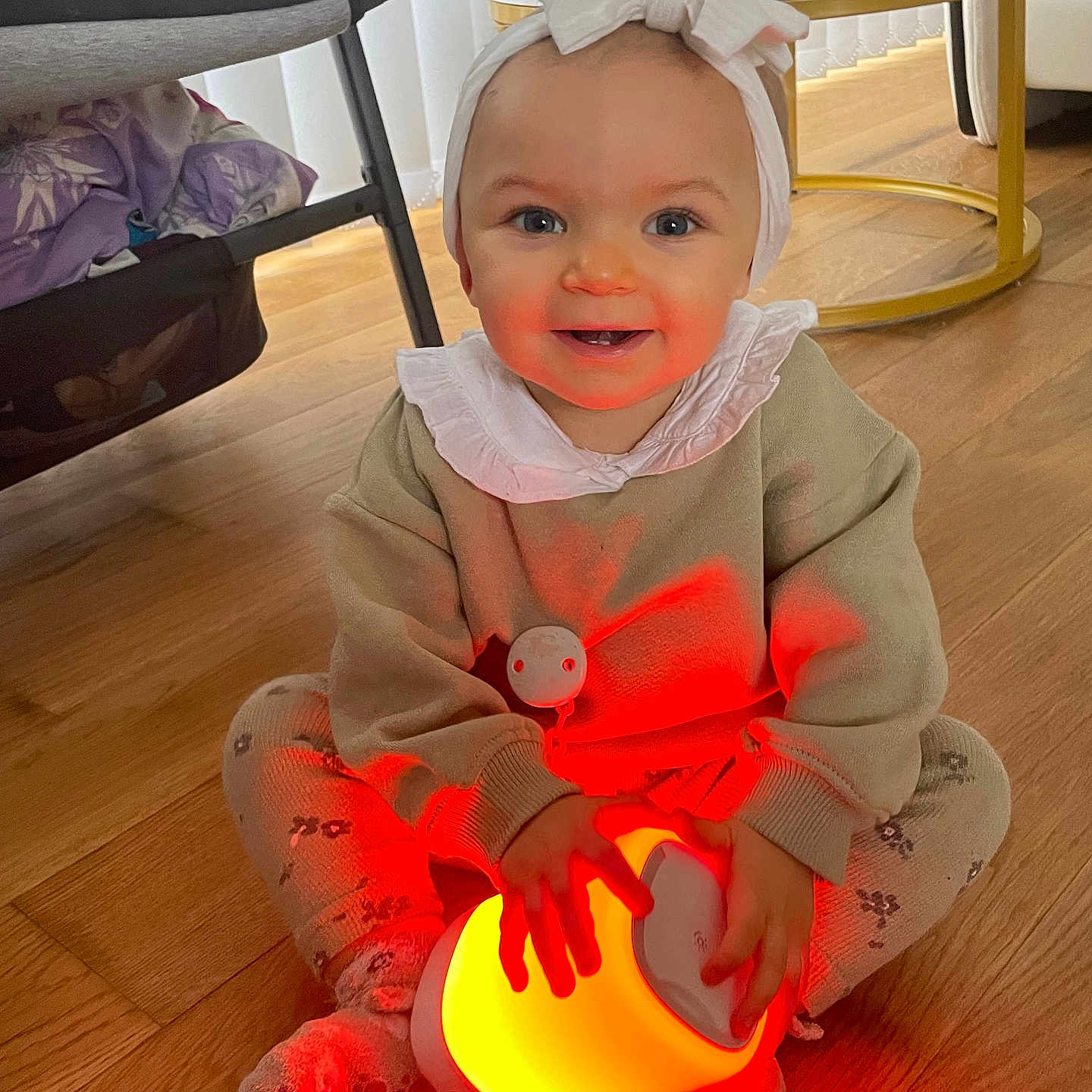 Loudjayne participe au concours pour gagner de l'argent avec cette photo : baby, bow, child, cozy, cute, face, floor, furniture, glowing_lamp, hands, happy, headband, indoors, leggings, patterned_clothing, remote_control, sitting, smiling, table, wooden_floor