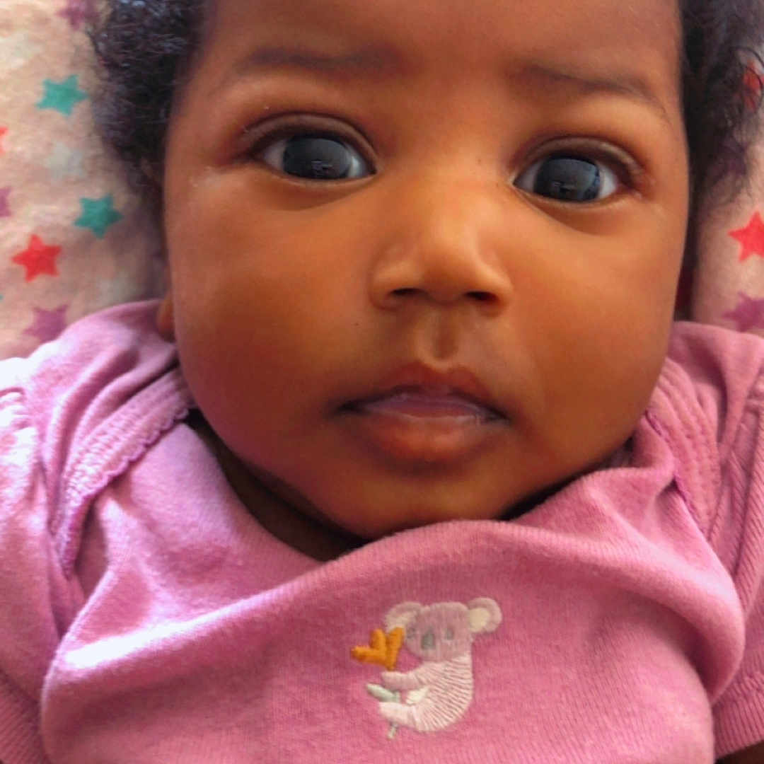 Ambrielle joined the competition — help win amazing prizes! baby, blanket, child, closeup, curly_hair, cute, expression, eyes, face, hand, indoors, infant, koala_embroidery, lying_down, onesie, pink_clothing, portrait, skin, star_pattern, young