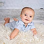baby, blue_eyes, smiling, fluffy_rug, striped_shirt, lying_down, curious, happy, indoor, portrait, infant, cute, child, wooden_background, soft_texture, crawling, head_up, baby_clothes, closeup, skin