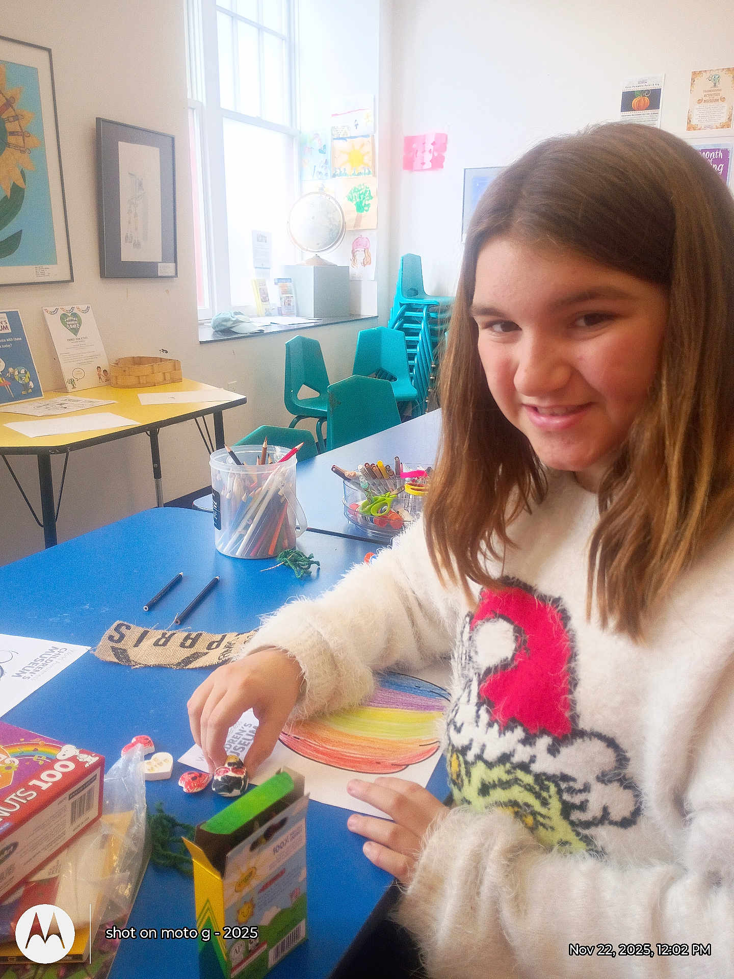 Sofia Burke joined the competition — help win amazing prizes! child, girl, art_project, coloring, markers, crayons, table, classroom, smile, sweater, indoor, crafts, drawing, happy, person, furniture, window, chair, stationery, creative