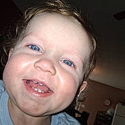 Adalynn joined the competition — help win amazing prizes! toddler, child, smiling, blue_eyes, curly_hair, close_up, indoor, baby_teeth, face, person, happy, casual_clothing, home, living_room, ceiling_fan, clock, furniture, light, photography, portrait