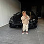 émilio participe au concours pour gagner de l'argent avec cette photo : child, boy, kid, car, sports_car, lamborghini, luxury, garage, concrete_floor, coat, smile, portrait, standing, shoes, head, blonde_hair, vehicle, headlights, tiled_floor, black_car