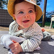 Jules participe au concours pour gagner de l'argent avec cette photo : baby, child, hat, striped_clothing, outdoor, smiling, blanket, hand, face, blue_sky, sunlight, garden, grass, wooden_structure, chair, happy, clothing, toddler, portrait, daylight