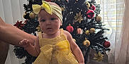Lietys joined the competition — help win amazing prizes! baby, child, yellow_dress, headband, socks, christmas_tree, ornaments, indoor, curtains, floor, hand, support, holiday, decorations, window, light, person, standing, festive, home