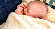 Braxton joined the competition — help win amazing prizes! newborn, baby, sleeping, infant, face, hand, blanket, swaddled, teddy_bear, plush, couch, cushion, indoor, portrait, cozy, peaceful, resting, pink_clothing, cream_blanket, close_up