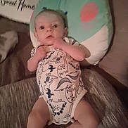 Braxton is registered to the contest to win money with this photo: baby, infant, child, portrait, sitting, onesie, dinosaur, frog, seat, cushion, indoor, home, keyboard, piano, brown_background, wide_eyes, hands, legs, cozy, photography