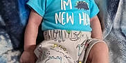 Emerson joined the competition — help win amazing prizes! baby, infant, smile, dinosaur, clothing, socks, blanket, pattern, blue, cute, child, person, lying_down, soft_texture, happy, casual, indoor, portrait, small_person, young