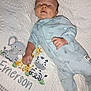 baby, infant, sleeping, onesie, blue_clothing, quilt, embroidery, elephant, giraffe, zebra, name, soft_texture, bed, resting, cute, child, newborn, peaceful, indoors, portrait
