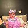 baby, infant, child, portrait, sitting, bed, pillow, dress, pink, bow, ruffles, indoor, bedroom, face, eyes, serious_expression, cute, blanket, furniture, photography
