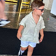 Matteo participe au concours pour gagner de l'argent avec cette photo : toddler, child, sunglasses, pacifier, shorts, shirt, sneakers, walking, indoor, floor, marble, person, motion_blur, fashion, casual, young_child, cute, hair, legs, adult