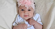 Kinsley is registered to the contest to win money with this photo: baby, blanket, calvin_klein, child, clothing, cozy, cute, fist, flower, headband, indoors, infant, lying_down, onesie, person, pink, portrait, smiling, soft, young