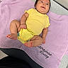 baby, infant, child, smiling, portrait, yellow_outfit, lavender_blanket, lying_down, seated, indoors, cozy, happy, face, arms, legs, bare_feet, knitwear, textile, furniture, photography
