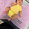 baby, child, infant, yellow_outfit, lavender_blanket, lying_down, sitting, portrait, face, smiling, wide_eyed, brown_hair, indoor, cozy, textile, chair, furniture, bare_feet, playful, photography