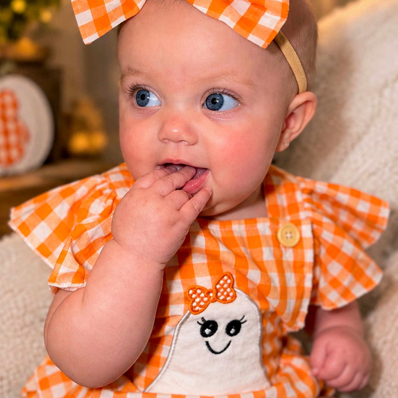 Kori joined the competition — help win amazing prizes! baby, infant, child, portrait, smiling, blue_eyes, bow, headband, gingham, orange, white, dress, bibs, hand, finger, sitting, indoors, chair, close_up, adorable