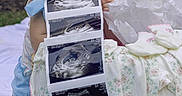 Kori is registered to the contest to win money with this photo: baby, infant, child, smiling, portrait, outdoor, garden, flowers, rose, blanket, baby_clothing, blue_clothing, floral_fabric, ultrasound, sonogram, pregnancy, sibling, paper, tissue_paper, family_announcement
