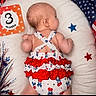 baby, infant, child, three_months, lying_down, portrait, milestone_photo, red_white_blue, patriotic, stars, cushion, white_blanket, dress, ruffles, hair, earring, festive, holiday, photography, indoor