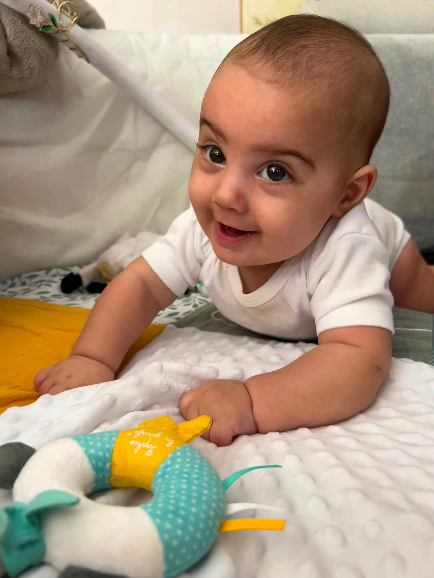 Léandros a rejoint le concours — aidez-le/la à gagner de superbes lots ! arm, baby, blanket, child, childhood, crawling, cute, face, floor, hand, happy, head, indoor, infant, playtime, plush_toy, smiling, soft_texture, toy, white_onesie