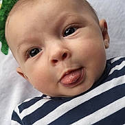 Sacha participe au concours pour gagner de l'argent avec cette photo : baby, tongue, striped_clothing, close_up, face, infant, child, playful, expression, lying_down, blanket, soft_texture, cute, person, portrait, skin, head, eyes, mouth, young