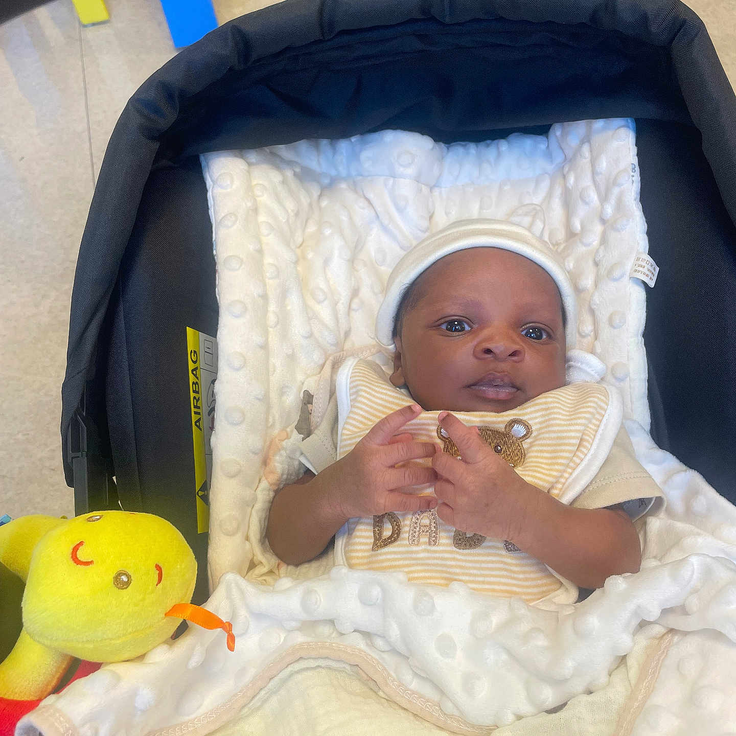 Jean-Isis participe au concours pour gagner de l'argent avec cette photo : baby, bib, blanket, car_seat, child, comfort, cozy, cute, face, hands, indoor, infant, looking, lying_down, newborn, person, plush_toy, soft_texture, wearing_hat, yellow_toy