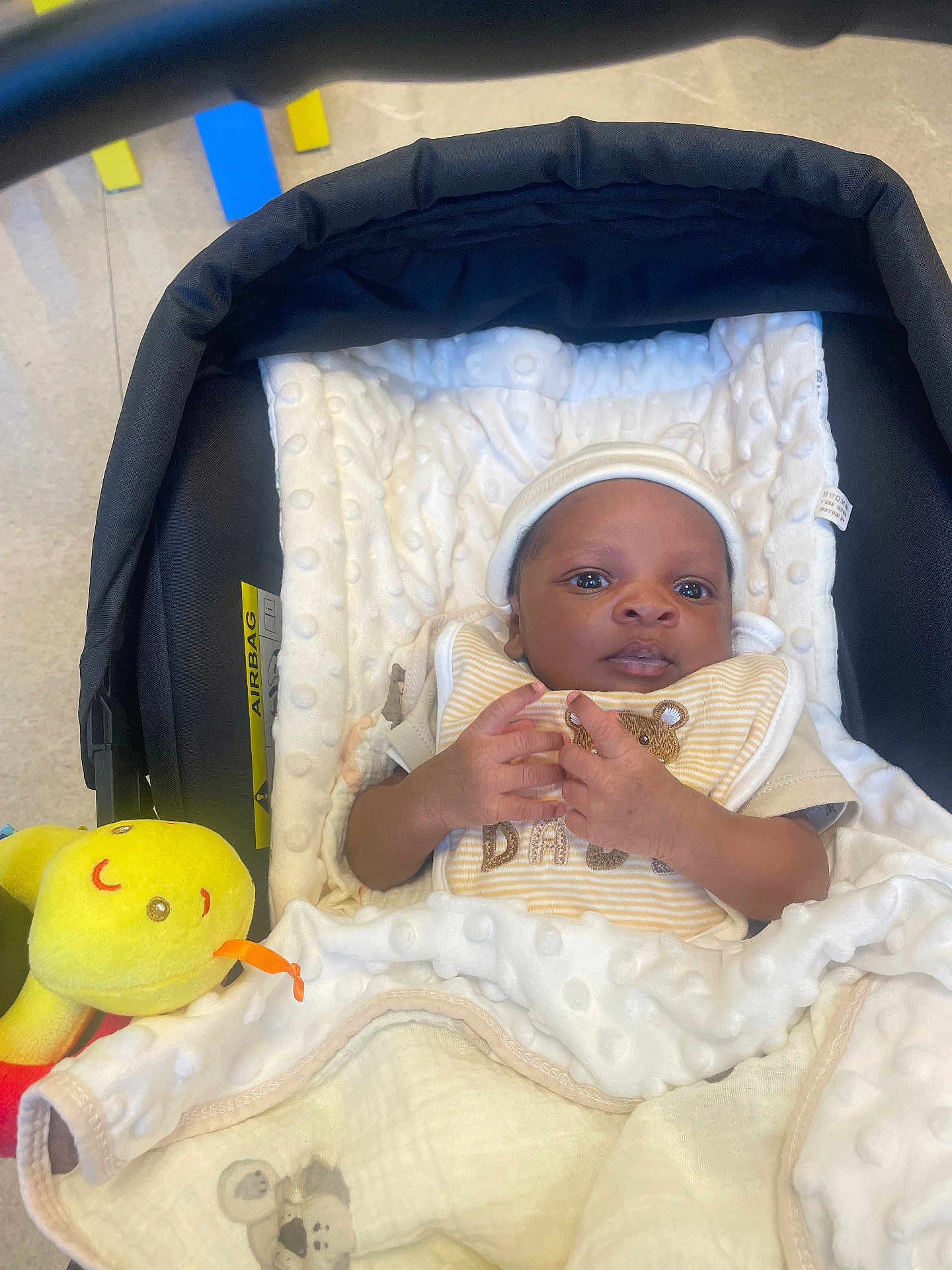 Jean-Isis participe au concours pour gagner de l'argent avec cette photo : baby, bib, blanket, car_seat, child, comfort, cozy, cute, face, hands, indoor, infant, looking, lying_down, newborn, person, plush_toy, soft_texture, wearing_hat, yellow_toy