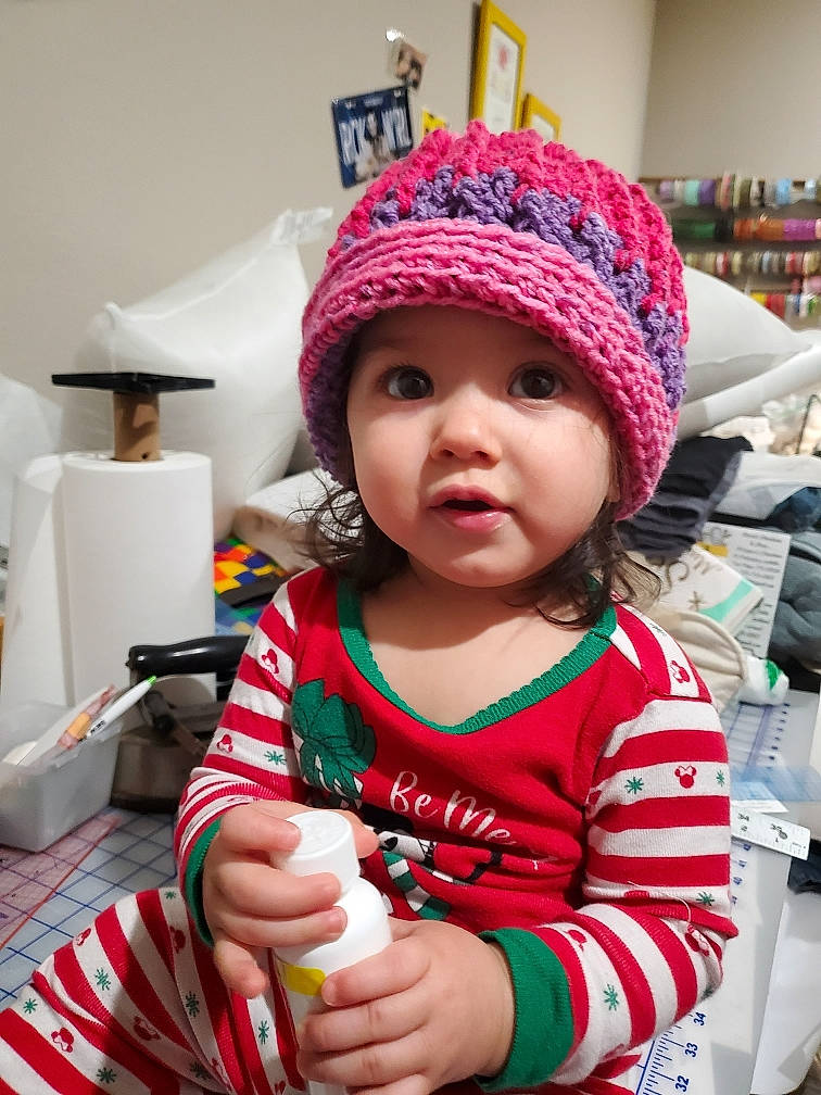 Stella is registered to the contest to win money with this photo: baby, baby_toddler_clothing, beanie, cap, child, christmas_eve, event, fashion_accessory, fun, headwear, helmet, holiday, knit_cap, lamp, magenta, person, pink, room, skin, toddler