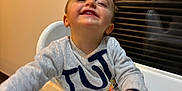 Paolo a rejoint le concours — aidez-le/la à gagner de superbes lots ! toddler, child, high_chair, smile, happy, indoor, baby, clothing, reaching, face, person, cheerful, furniture, table, sitting, wood_floor, light, home, cute, portrait