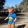 toddler, child, boy, outdoor, sunny, walking, blue_shirt, pants, shadow, nature, trees, fence, daylight, curious, young_child, casual_clothing, grass, path, short_hair, socks