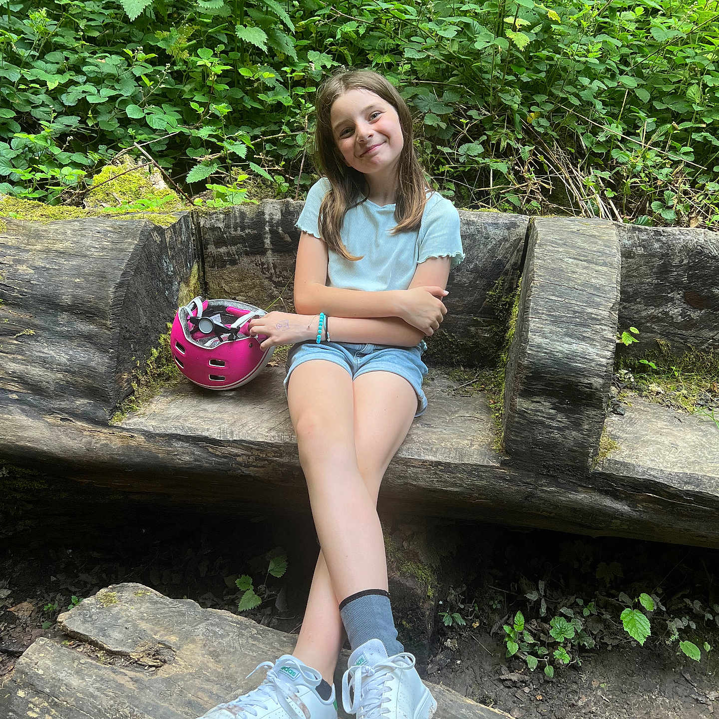 Kimberly a rejoint le concours — aidez-le/la à gagner de superbes lots ! bench, casual_clothing, child, daylight, forest, girl, greenery, helmet, nature, outdoor, pink_helmet, plants, relaxed, seated, shorts, smiling, socks, tshirt, white_sneakers, wooden_bench