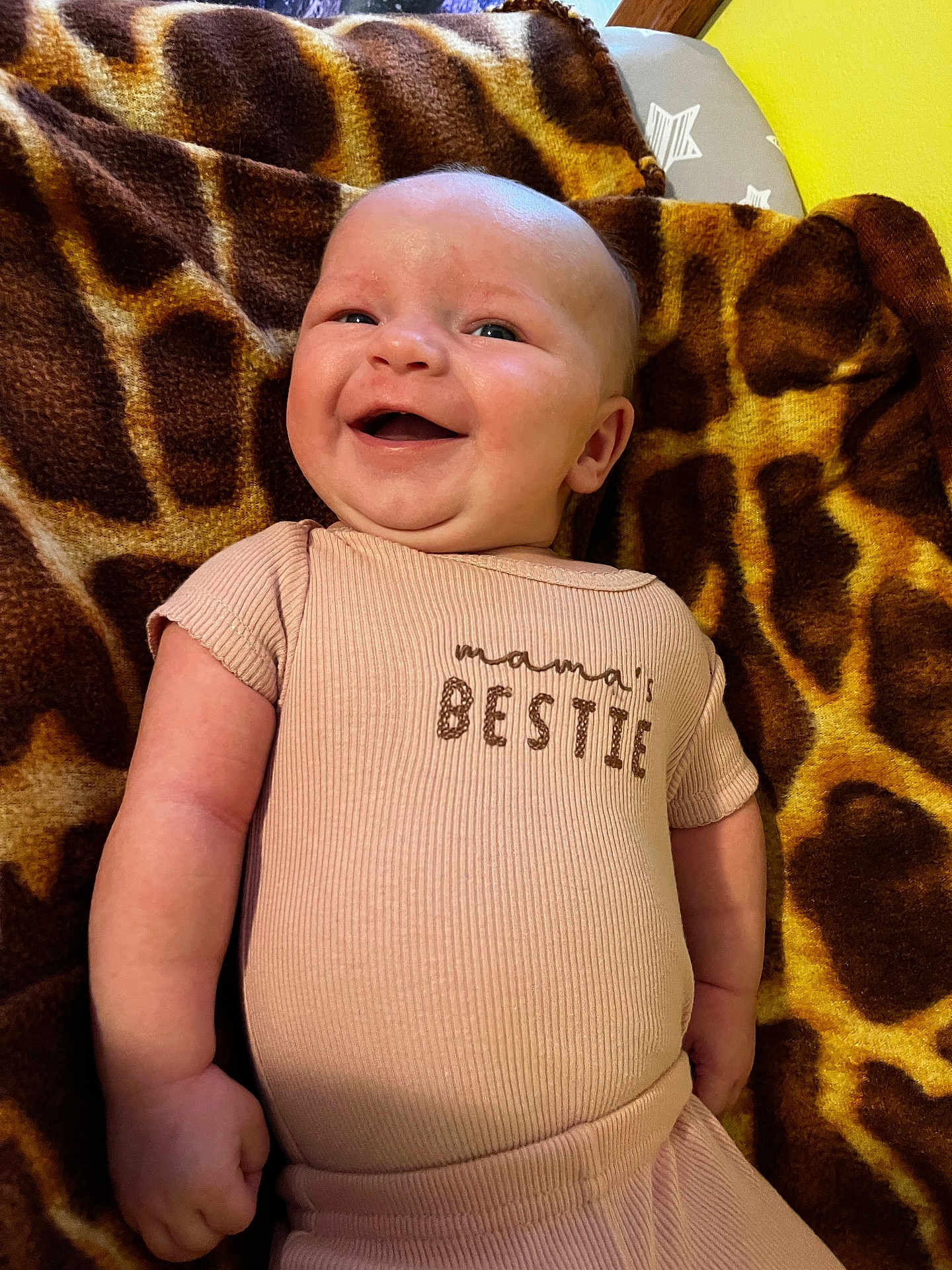 Khaleesi joined the competition — help win amazing prizes! baby, smiling, infant, cute, apparel, onesie, giraffe_pattern, blanket, happy, child, face, skin, person, lying_down, indoors, cheerful, cute_outfit, newborn, expression, soft_texture