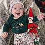 baby, child, infant, smiling, holiday_clothing, christmas_pajamas, hat, elf_doll, faux_fur_blanket, christmas_tree, ornaments, decorations, happy, indoors, festive, toy, person, portrait, seasonal, cute