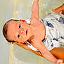 Elio participe au concours pour gagner de l'argent avec cette photo : baby, infant, water, bath, hands, cloth, white_cloth, blue_pattern, skin, arm, face, eyes, newborn, support, care, child, person, human, bath_time, wet