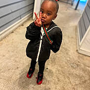 Kelani joined the competition — help win amazing prizes! child, peace_sign, black_jacket, red_bow, sneakers, standing, alleyway, concrete_floor, earrings, shoulder_bag, person, fashion, cute, outdoor, portrait, young_child, expression, casual_wear, urban, playful