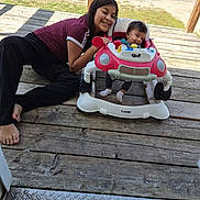 Julio joined the competition — help win amazing prizes! baby, barefoot, casual_clothing, child, daylight, family, footwear, grass, happy, infant, outdoor, person, playtime, porch, sitting, smiling, toy, walker, wood, young_girl