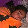 animal, bat_pattern, bed, black_dog, blanket, comfort, cozy, dog, face, home, indoor, lying_down, orange_blanket, person, pet, pillow, portrait, purple_light, sleepy, snuggle