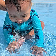 Elias joined the competition — help win amazing prizes! toddler, child, water, splashing, pool, blue_swimsuit, wet_hair, summer, outdoor, playing, happy, fun, sunlight, water_droplets, shallow_water, person, background_people, trees, daytime, vacation