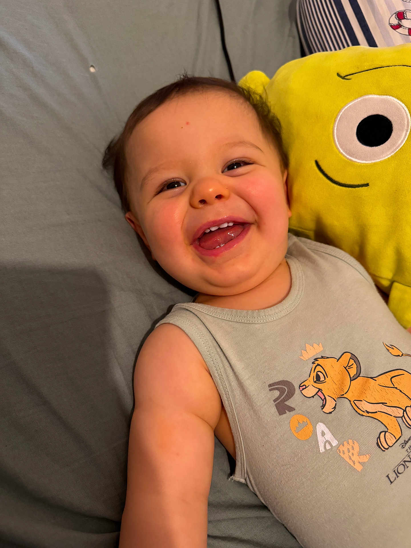 Léo participe au concours pour gagner de l'argent avec cette photo : baby, smiling, face, child, plush_toy, yellow, bed, clothing, sleeveless_shirt, lion_king, cartoon, happy, cute, indoors, person, portrait, toy, childhood, infant, sleeping_area