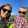 Valentin participe au concours pour gagner de l'argent avec cette photo : child, woman, sunglasses, outdoor, smile, holding_hands, greenery, blue_sky, plaid_shirt, casual_clothing, sunlight, happy, portrait, nature, family, playground, daylight, grass, tree, leisure