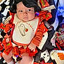 Aleea is registered to the contest to win money with this photo: baby, infant, child, halloween, candy, reese's, hershey's, kitkat, bib, hat, blanket, sock, orange_clothing, black_knit_hat, lying_down, holiday, cute, indoors, food, celebration
