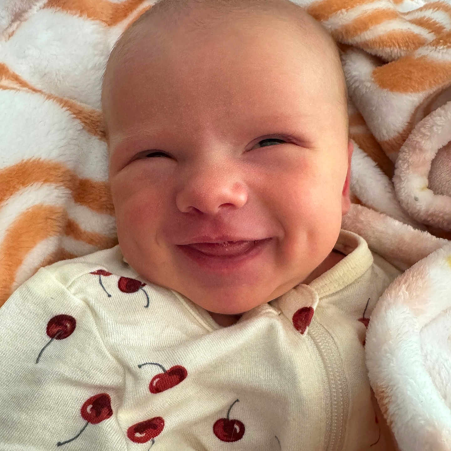 Aleea joined the competition — help win amazing prizes! baby, blanket, cheek, cherry, clothing, cozy, cute, face, happy, infant, lying_down, newborn, onesie, pattern, portrait, red, skin, smile, soft, white