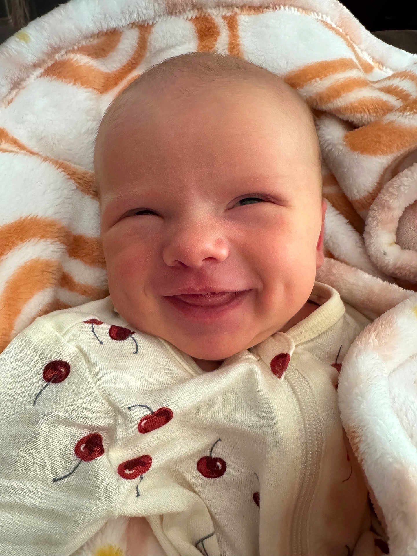Aleea joined the competition — help win amazing prizes! baby, smile, face, blanket, clothing, infant, cheek, onesie, pattern, red, white, cozy, happy, cute, skin, portrait, newborn, lying_down, cherry, soft