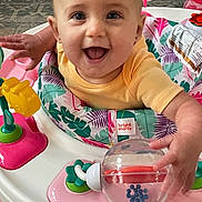 Nora is registered to the contest to win money with this photo: baby, child, smiling, face, eyes, hands, toy, walker, activity_center, colorful, yellow_shirt, happy, indoor, floor, plastic_toy, play, infant, cute, joyful, person